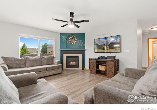 3816 Partridge Ct, Evans, CO 80620 - living room featuring wood finished floors, a tiled fireplace, and a ceiling fan