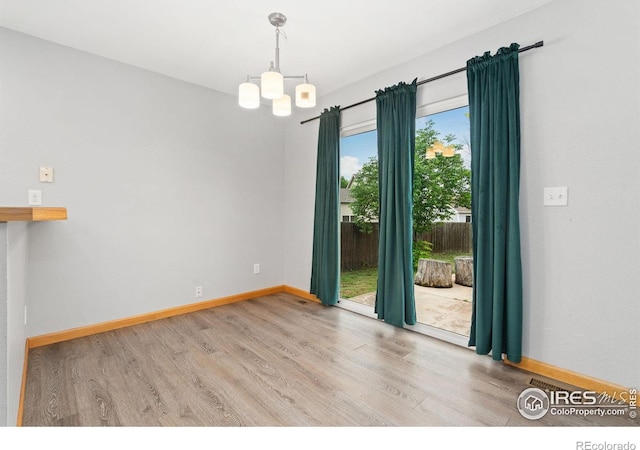 3816 Partridge Ct, Evans, CO 80620 - spare room with wood finished floors, baseboards, and a chandelier