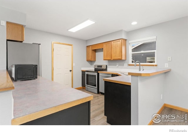 3816 Partridge Ct, Evans, CO 80620 - kitchen featuring appliances with stainless steel finishes, a sink, a peninsula, light countertops, and recessed lighting