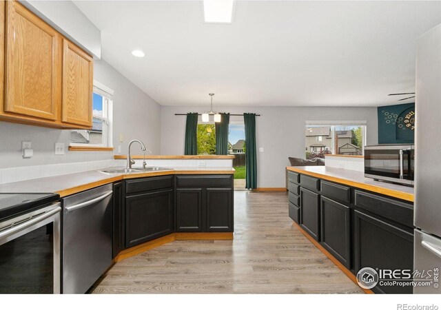 3816 Partridge Ct, Evans, CO 80620 - kitchen featuring appliances with stainless steel finishes, a sink, a peninsula, light wood-type flooring, and light countertops