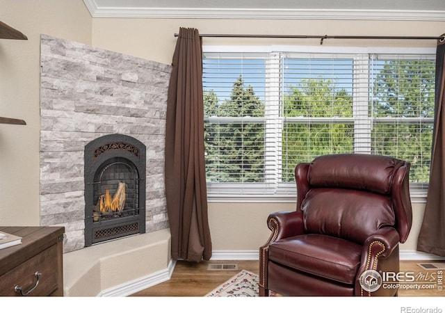 1892 Bell Dr, Erie, CO 80516 - sitting room featuring a warm lit fireplace, wood finished floors, baseboards, and ornamental molding