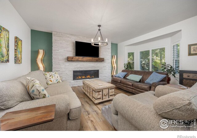 1892 Bell Dr, Erie, CO 80516 - living area with hardwood / wood-style floors, a stone fireplace, and a chandelier