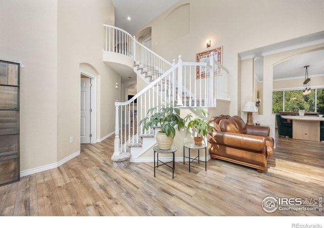 1892 Bell Dr, Erie, CO 80516 - living area with stairway, arched walkways, wood finished floors, a high ceiling, and baseboards