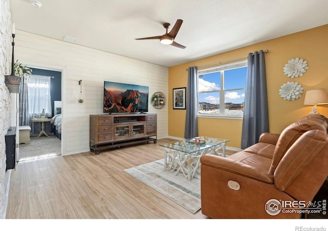 296 Swallow Rd, Johnstown, CO 80534 - living area featuring an accent wall, a ceiling fan, wood walls, wood finished floors, and baseboards