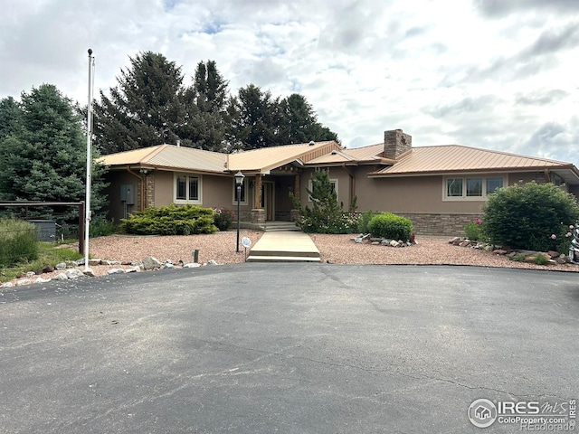 33180 Pikes Peak Dr, Greeley, CO 80631 - ranch-style home featuring stucco siding, a chimney, metal roof, and stone siding