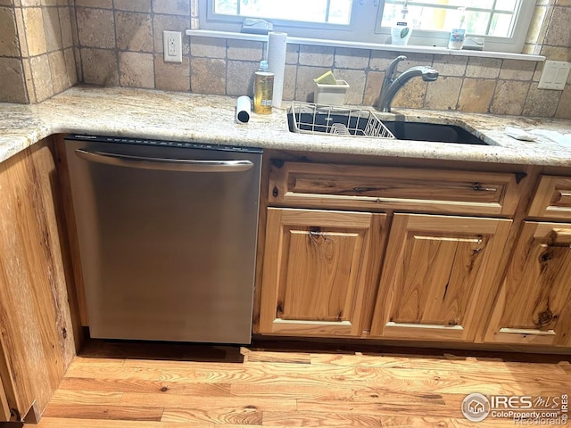 33180 Pikes Peak Dr, Greeley, CO 80631 - kitchen with stainless steel dishwasher, a sink, brown cabinets, tasteful backsplash, and light stone counters