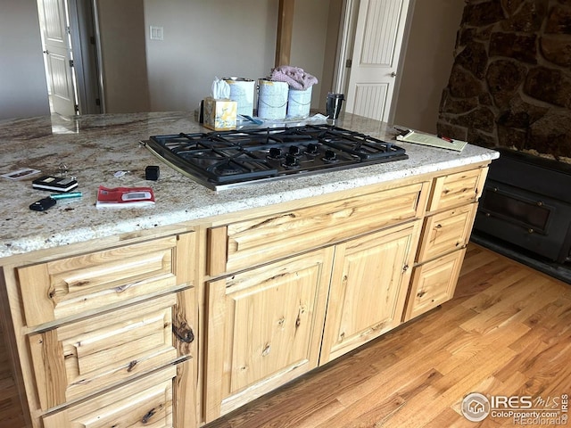 33180 Pikes Peak Dr, Greeley, CO 80631 - kitchen featuring gas cooktop, light wood finished floors, light brown cabinetry, and light stone countertops