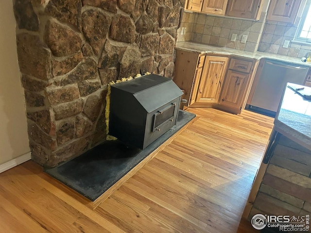 33180 Pikes Peak Dr, Greeley, CO 80631 - kitchen view of light wood-type flooring, a wood stove, tasteful backsplash, light stone counters, and baseboards