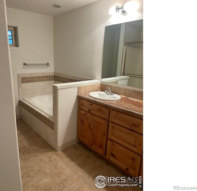 33180 Pikes Peak Dr, Greeley, CO 80631 - full bath with vanity, a garden tub, a textured wall, a textured ceiling, and an enclosed shower