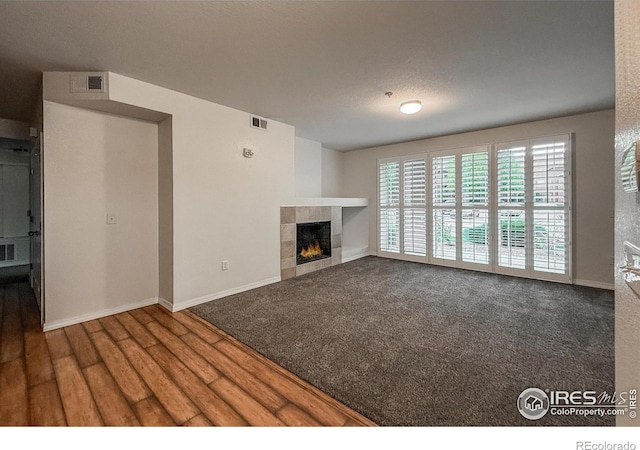 804 Summer Hawk Dr Unit 105, Longmont, CO 80504 - unfurnished living room featuring a tiled fireplace, baseboards, and wood finished floors