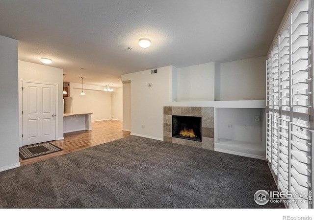 804 Summer Hawk Dr Unit 105, Longmont, CO 80504 - unfurnished living room with carpet floors, a fireplace, baseboards, and a textured ceiling