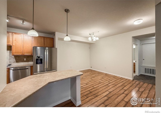 804 Summer Hawk Dr Unit 105, Longmont, CO 80504 - kitchen with appliances with stainless steel finishes, dark wood finished floors, backsplash, baseboards, and pendant lighting