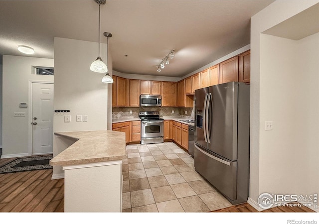 804 Summer Hawk Dr Unit 105, Longmont, CO 80504 - kitchen with appliances with stainless steel finishes, a peninsula, light countertops, backsplash, and pendant lighting