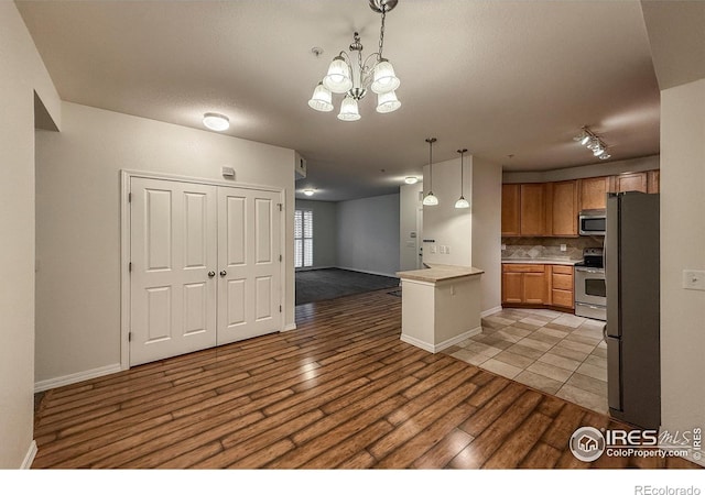 804 Summer Hawk Dr Unit 105, Longmont, CO 80504 - kitchen featuring stainless steel appliances, open floor plan, light wood-style flooring, backsplash, and light countertops