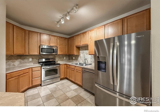 804 Summer Hawk Dr Unit 105, Longmont, CO 80504 - kitchen with appliances with stainless steel finishes, a sink, light countertops, light tile patterned flooring, and tasteful backsplash