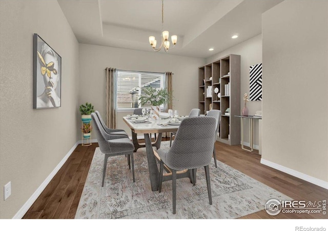 1368 Waterfall St, Timnath, CO 80547 - dining area with wood finished floors, a chandelier, a raised ceiling, baseboards, and recessed lighting