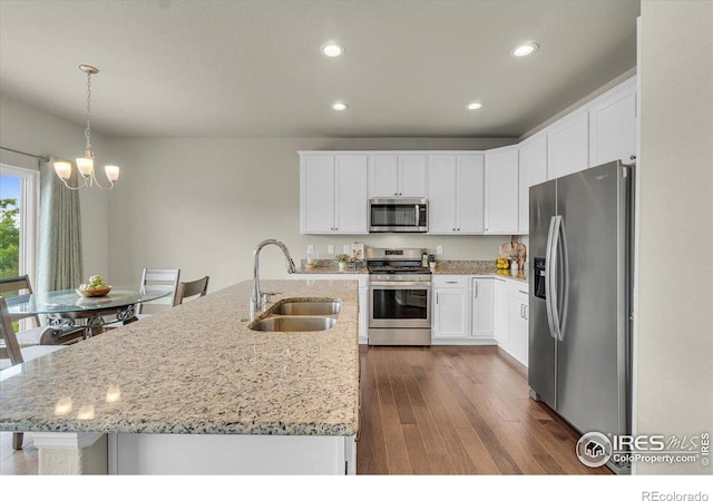 1368 Waterfall St, Timnath, CO 80547 - kitchen with stainless steel appliances, a sink, a chandelier, dark wood-style floors, and white cabinetry