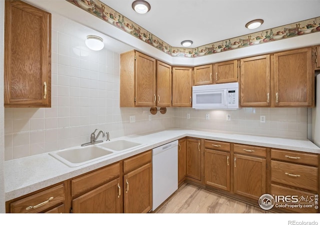 3641 Wild Horse Ct, Loveland, CO 80538 - kitchen with white appliances, a sink, brown cabinetry, backsplash, and light countertops