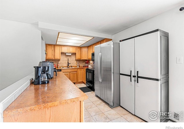 928 Michael Ave, Fort Morgan, CO 80701 - kitchen featuring freestanding refrigerator, black electric range, a sink, backsplash, and light tile patterned floors