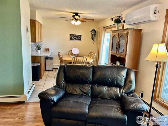 1722 Pheasant Rdg, Sterling, CO 80751 - living room featuring a wall mounted air conditioner, ceiling fan, a textured ceiling, baseboard heating, and light tile patterned floors