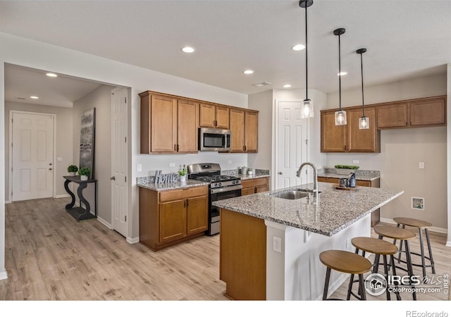 17871 E 96th Pl, Commerce City, CO 80022 - kitchen featuring stainless steel appliances, a sink, brown cabinets, light wood-style flooring, and recessed lighting