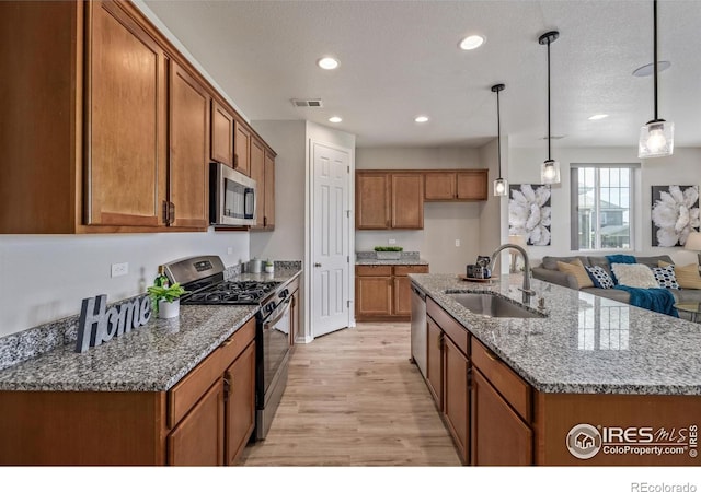 17871 E 96th Pl, Commerce City, CO 80022 - kitchen with stainless steel appliances, a sink, brown cabinets, light wood-type flooring, and pendant lighting