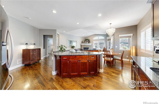6945 N Fargo Trl, Littleton, CO 80125 - kitchen featuring freestanding refrigerator, dark brown cabinets, dark wood finished floors, a fireplace, and a chandelier