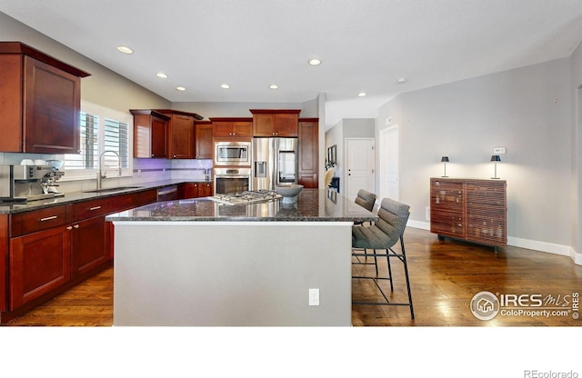 6945 N Fargo Trl, Littleton, CO 80125 - kitchen with stainless steel appliances, a kitchen island, dark wood-type flooring, a breakfast bar, and recessed lighting