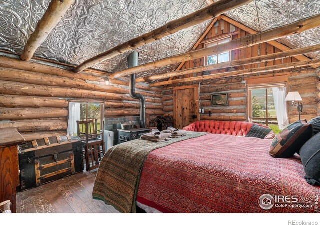 6600 State Highway 7, Estes Park, CO 80517 - bedroom featuring hardwood / wood-style flooring, a wood stove, rustic walls, and high vaulted ceiling