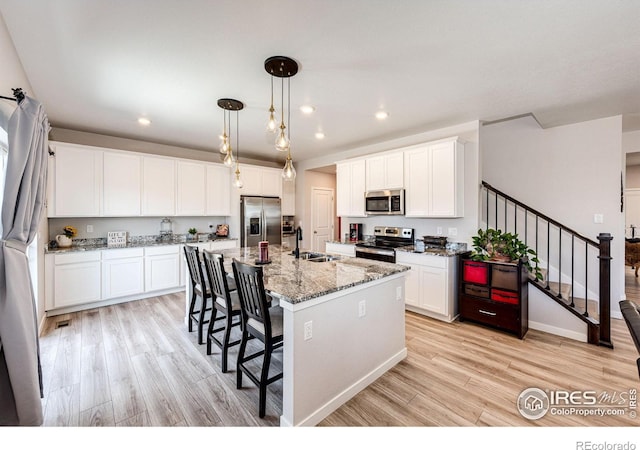 1191 Horsetail Loop, Elizabeth, CO 80107 - kitchen with appliances with stainless steel finishes, a sink, light wood-style flooring, a kitchen breakfast bar, and recessed lighting