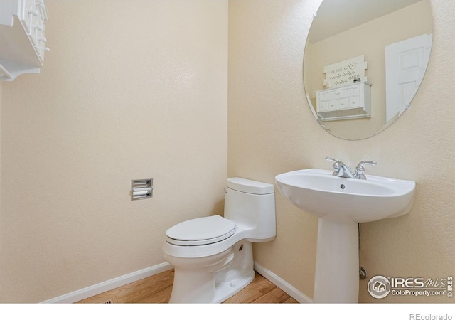 10216 Sandy Ridge Ct, Firestone, CO 80504 - half bathroom with wood finished floors, toilet, baseboards, and a sink