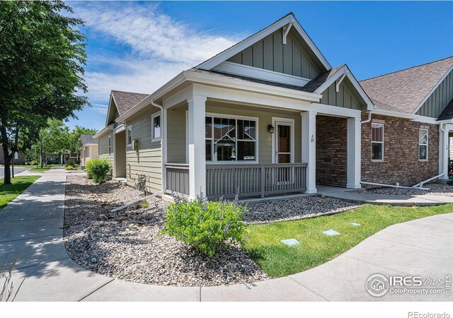 4751 Pleasant Oak Dr Unit A28, Fort Collins, CO 80525 - view of front of house featuring board and batten siding, covered porch, a shingled roof, and stone siding