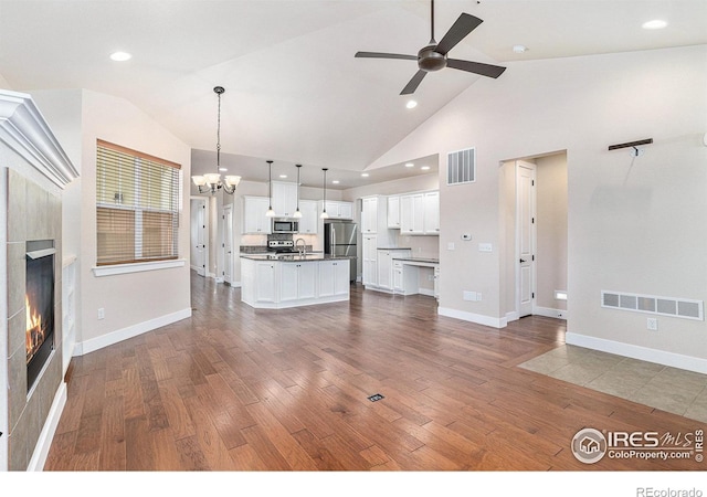 4751 Pleasant Oak Dr Unit A28, Fort Collins, CO 80525 - unfurnished living room with dark wood-style floors, a chandelier, a tile fireplace, ceiling fan, and baseboards
