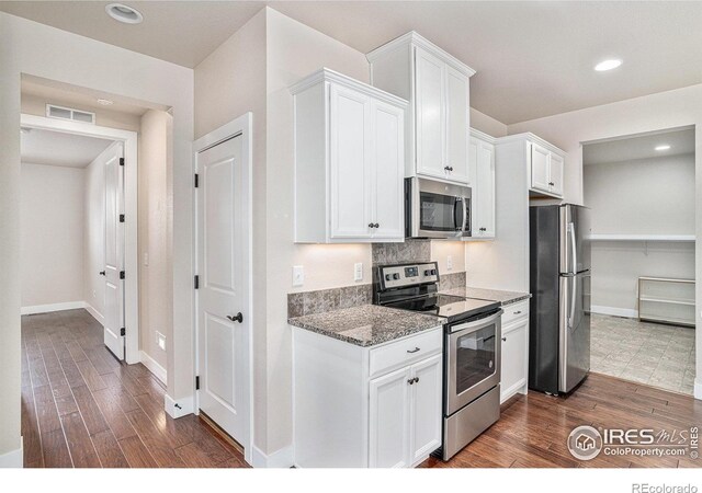 4751 Pleasant Oak Dr Unit A28, Fort Collins, CO 80525 - kitchen featuring appliances with stainless steel finishes, dark wood finished floors, white cabinetry, stone counters, and baseboards