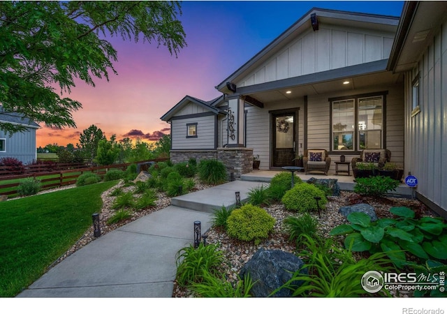 5966 Sunny Crest Dr, Timnath, CO 80547 - view of front of property with a porch, board and batten siding, a yard, and stone siding