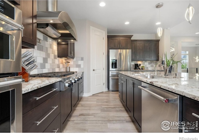 5966 Sunny Crest Dr, Timnath, CO 80547 - kitchen with stainless steel appliances, wall chimney range hood, a sink, dark brown cabinetry, and decorative backsplash