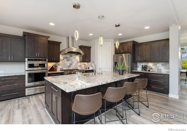 5966 Sunny Crest Dr, Timnath, CO 80547 - kitchen with ventilation hood, stainless steel appliances, a warming drawer, a kitchen breakfast bar, and light wood finished floors