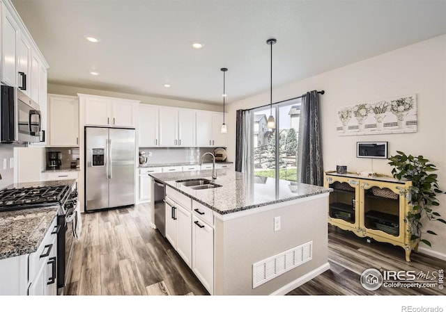 12889 Clearview St, Firestone, CO 80504 - kitchen with appliances with stainless steel finishes, wood finished floors, white cabinetry, stone counters, and recessed lighting