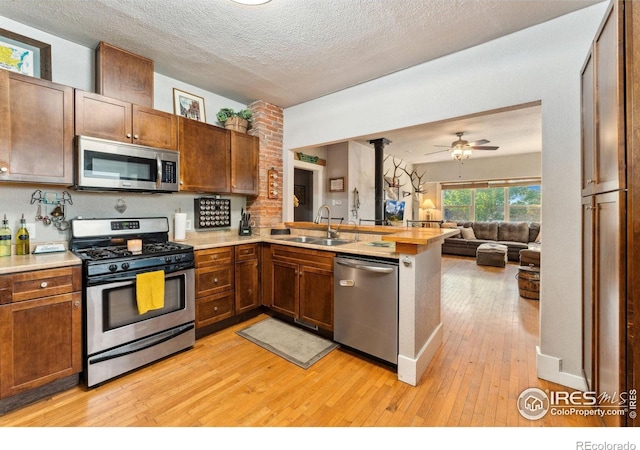 4900 W 6th Ave, Denver, CO 80204 - kitchen with stainless steel appliances, a sink, a peninsula, open floor plan, and light wood-type flooring