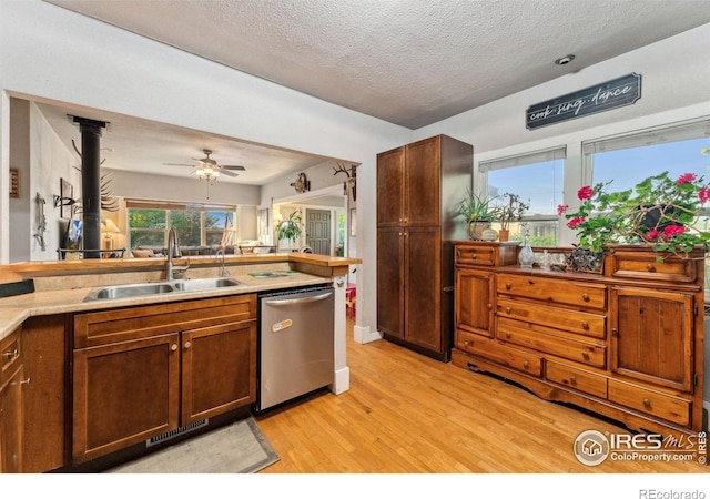 4900 W 6th Ave, Denver, CO 80204 - kitchen with dishwasher, a sink, light wood-style flooring, a textured ceiling, and a ceiling fan