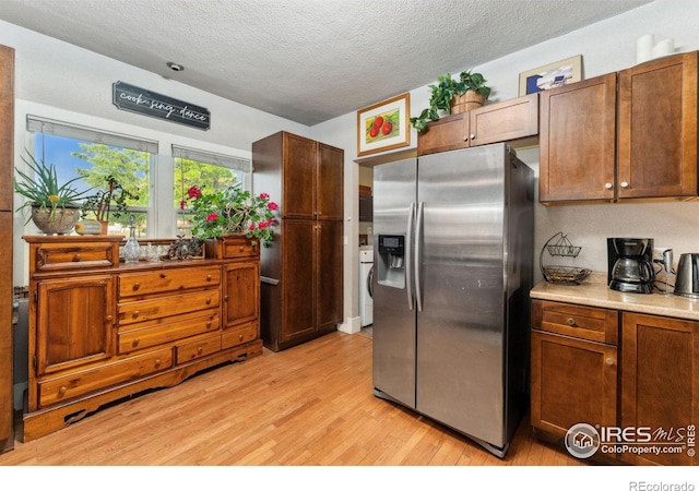 4900 W 6th Ave, Denver, CO 80204 - kitchen with stainless steel fridge with ice dispenser, light wood-style floors, a textured ceiling, light countertops, and washer / clothes dryer