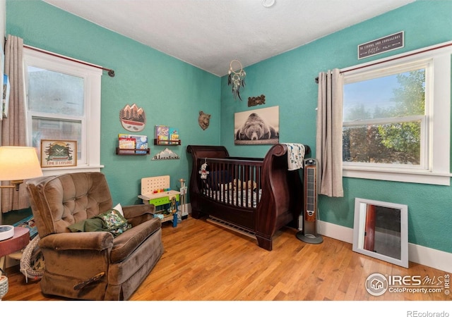 4900 W 6th Ave, Denver, CO 80204 - bedroom featuring wood finished floors, a crib, and baseboards