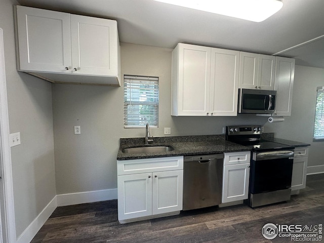 611 N 2nd St, Sterling, CO 80751 - kitchen with stainless steel appliances, a sink, baseboards, and white cabinets