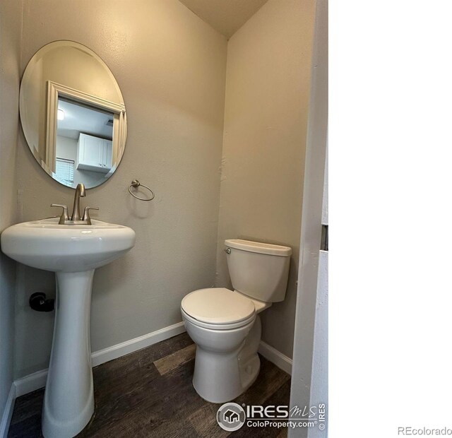 611 N 2nd St, Sterling, CO 80751 - bathroom with wood finished floors, toilet, baseboards, and a sink