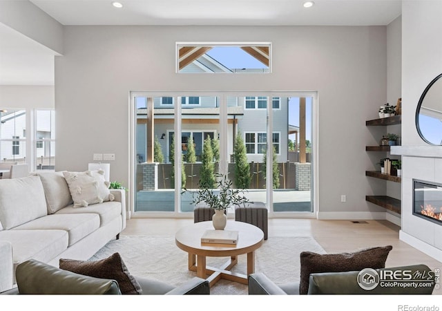1425 Burt Ave, Berthoud, CO 80513 - living area featuring plenty of natural light, a tiled fireplace, recessed lighting, wood finished floors, and baseboards