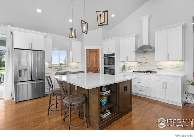 505 Nesting Eagles Way, Berthoud, CO 80513 - kitchen featuring stainless steel appliances, wall chimney exhaust hood, a kitchen island, tasteful backsplash, and white cabinetry