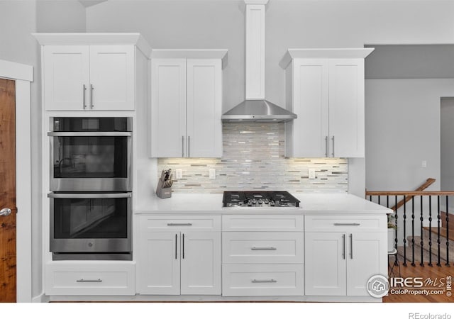 505 Nesting Eagles Way, Berthoud, CO 80513 - kitchen with appliances with stainless steel finishes, wall chimney exhaust hood, white cabinets, decorative backsplash, and light countertops