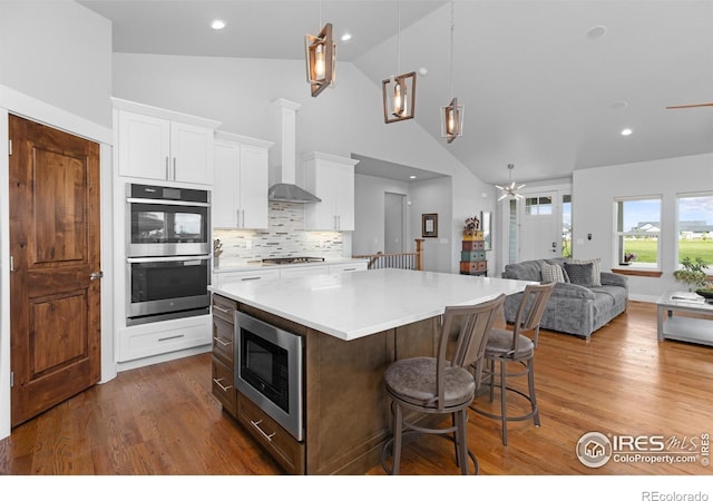 505 Nesting Eagles Way, Berthoud, CO 80513 - kitchen featuring stainless steel appliances, ceiling fan, open floor plan, a center island, and high vaulted ceiling