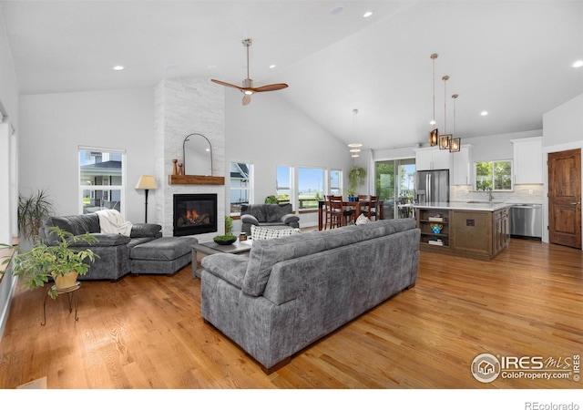 505 Nesting Eagles Way, Berthoud, CO 80513 - living area with high vaulted ceiling, light wood finished floors, a fireplace, and a ceiling fan