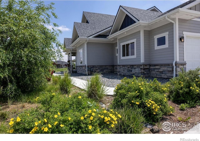 505 Nesting Eagles Way, Berthoud, CO 80513 - view of side of home featuring a shingled roof, stone siding, and a garage